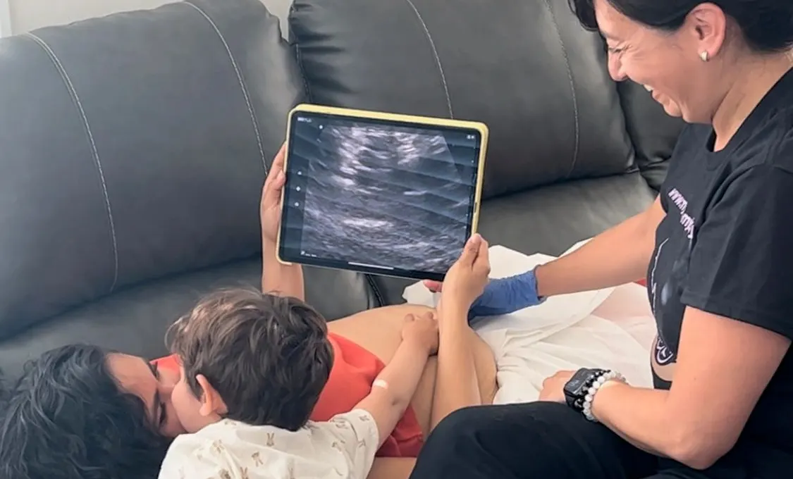 A mother and her toddler looking at an ultrasound image on a tablet