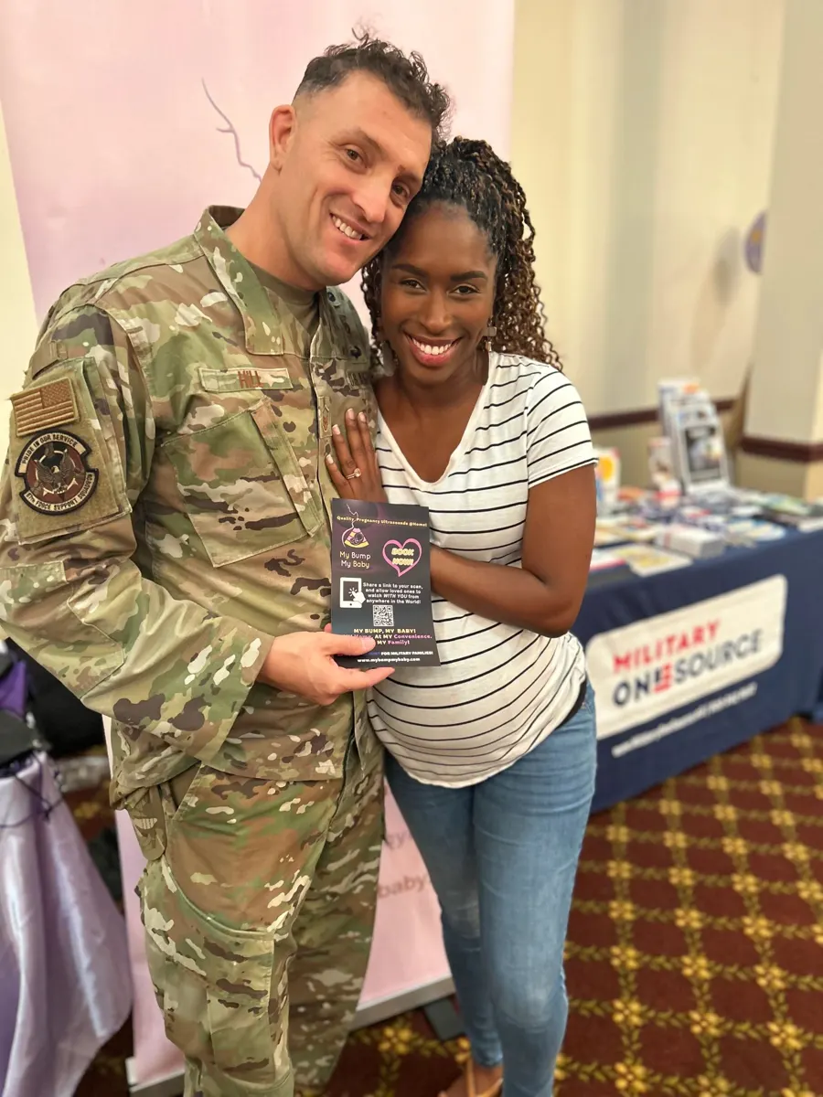 A smiling military father in uniform and a mother holding their ultrasound photo at a My Bump My Baby event